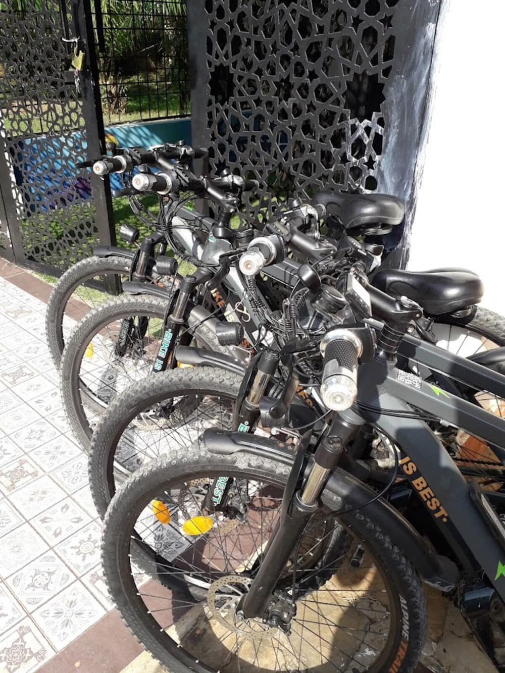 A row of electric bikes parked on a tiled porch