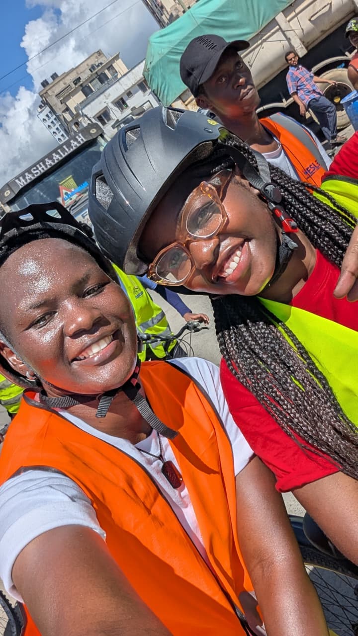 Two young women riders in helmets and hi-vis vests smiling for a selfie on the girls' ride