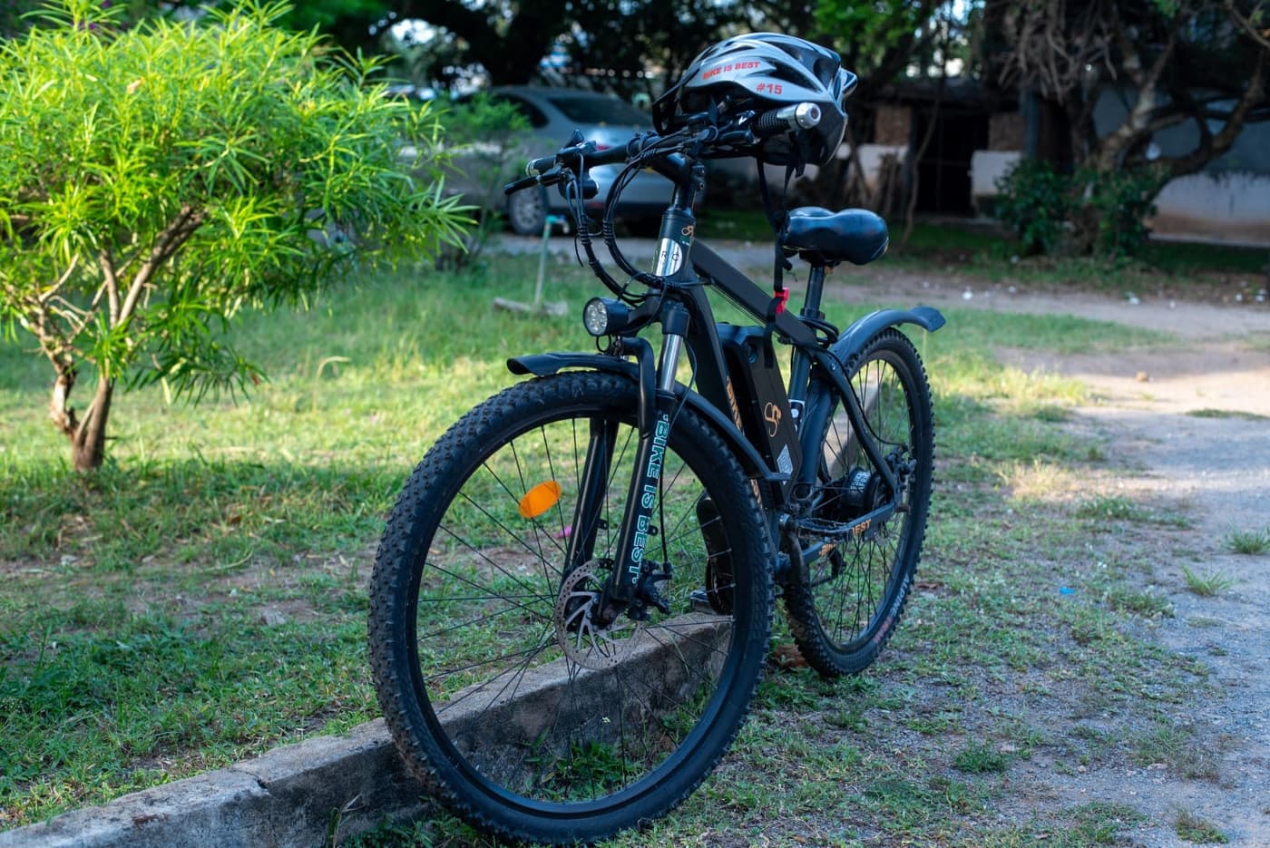 A Bike is Best electric bike with a helmet hung on the handlebars, parked on the grass at the hub