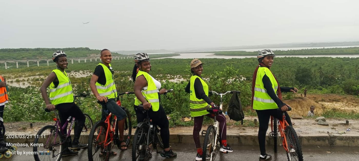 Riders in hi-vis vests pausing at a railing overlooking the water on a ride out to the SGR terminus