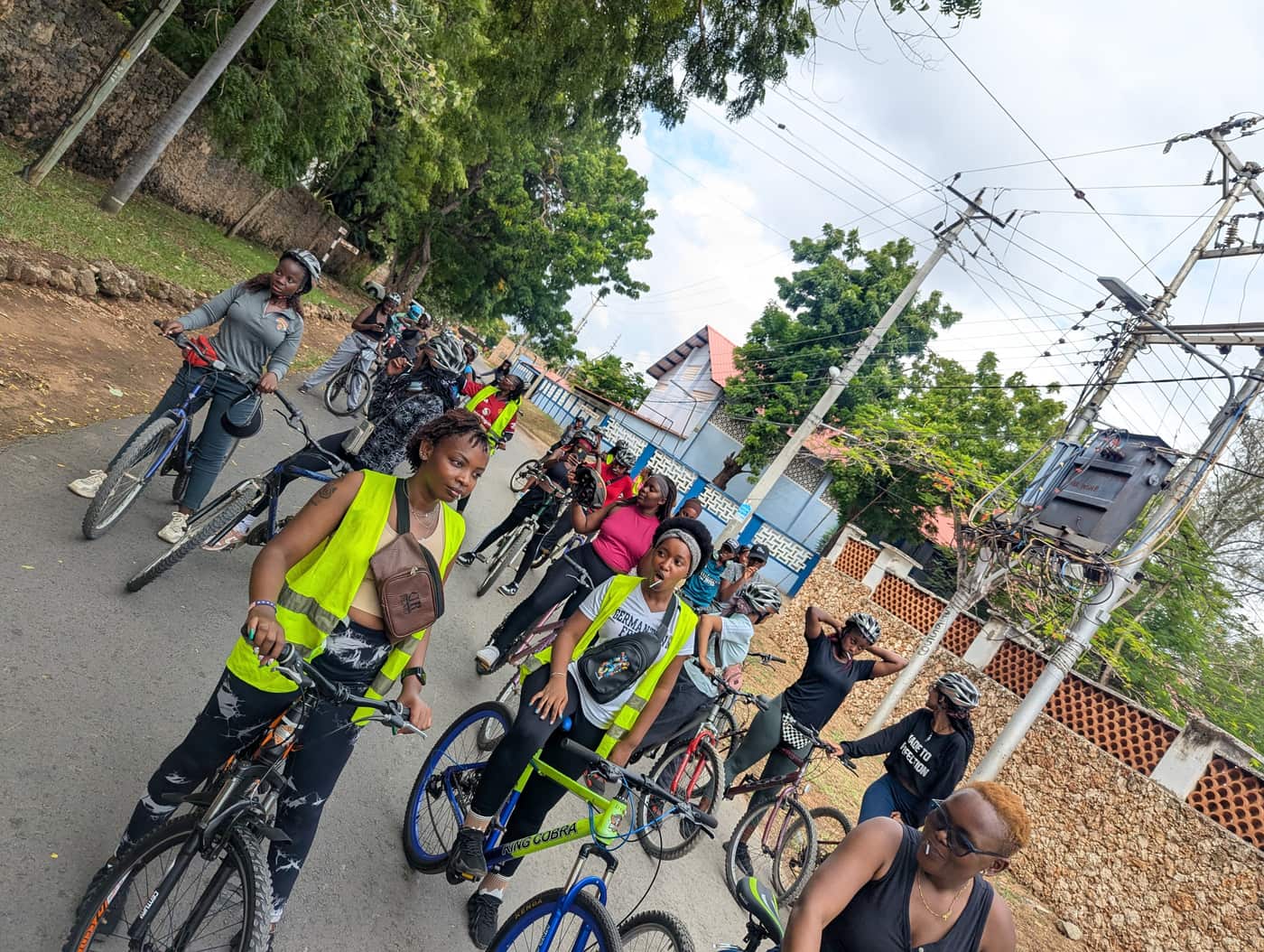 Riders on the monthly girls' ride in hi-vis vests laughing together on a Nyali road